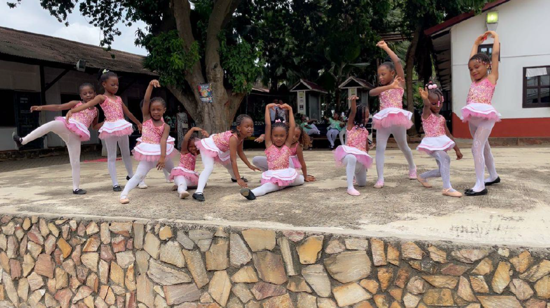 Young girl performing ballet pose outdoors in mint green costume