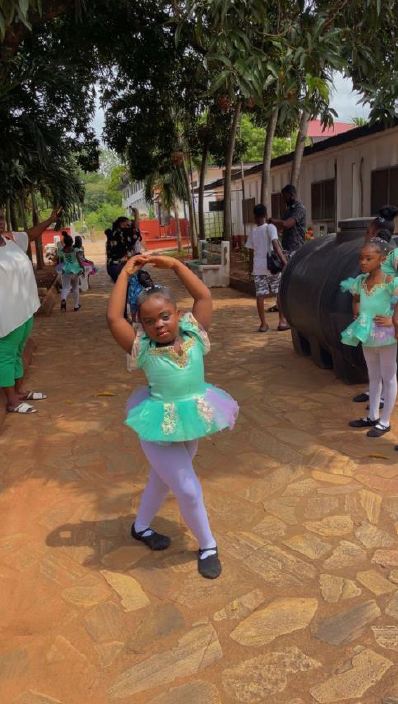 Four young girls in ballet costumes seated on stone wall with floral headbands
